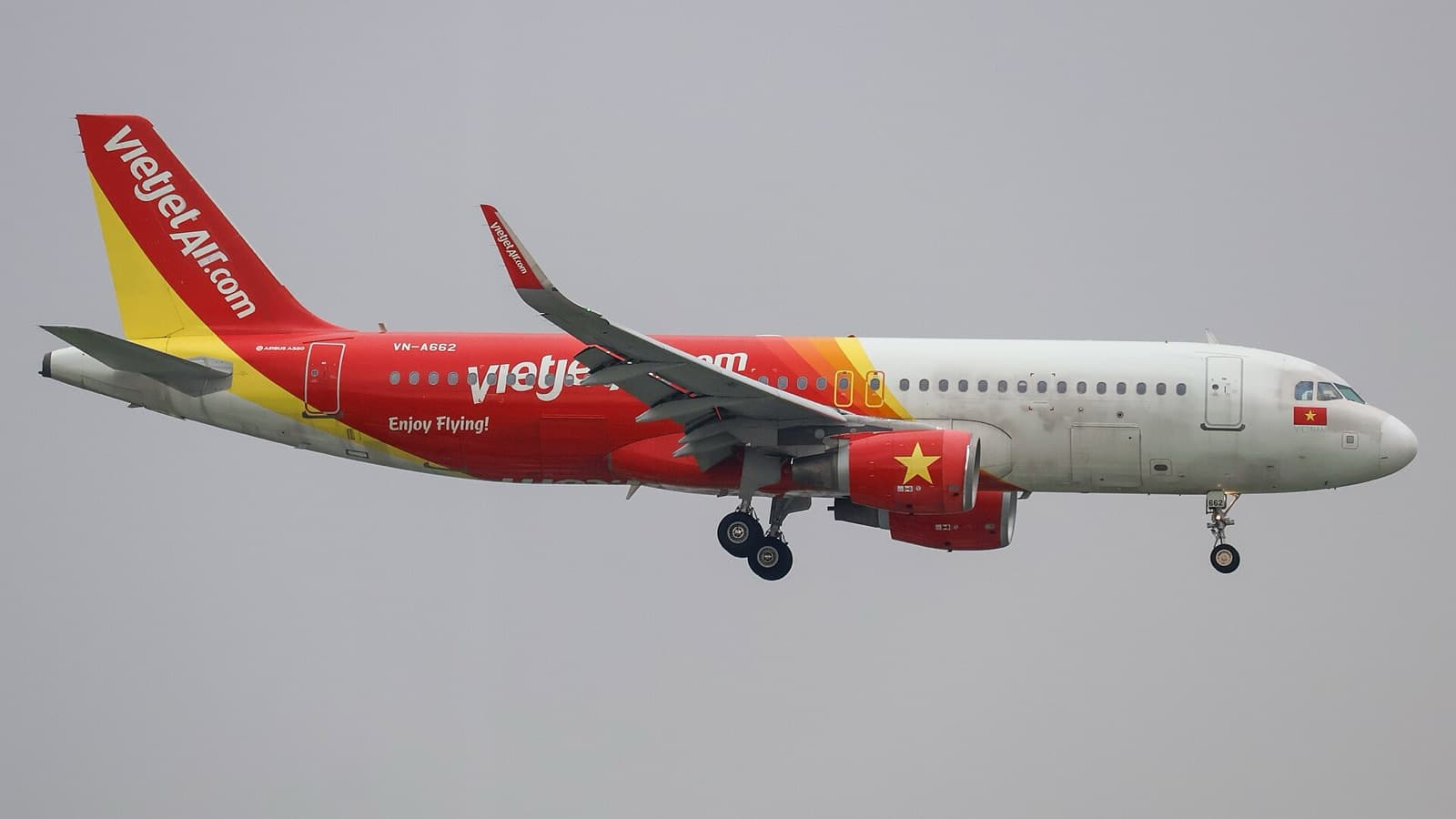 Airbus A320 Vietjet в красно-белой ливрее заходит на посадку в Таншоннят